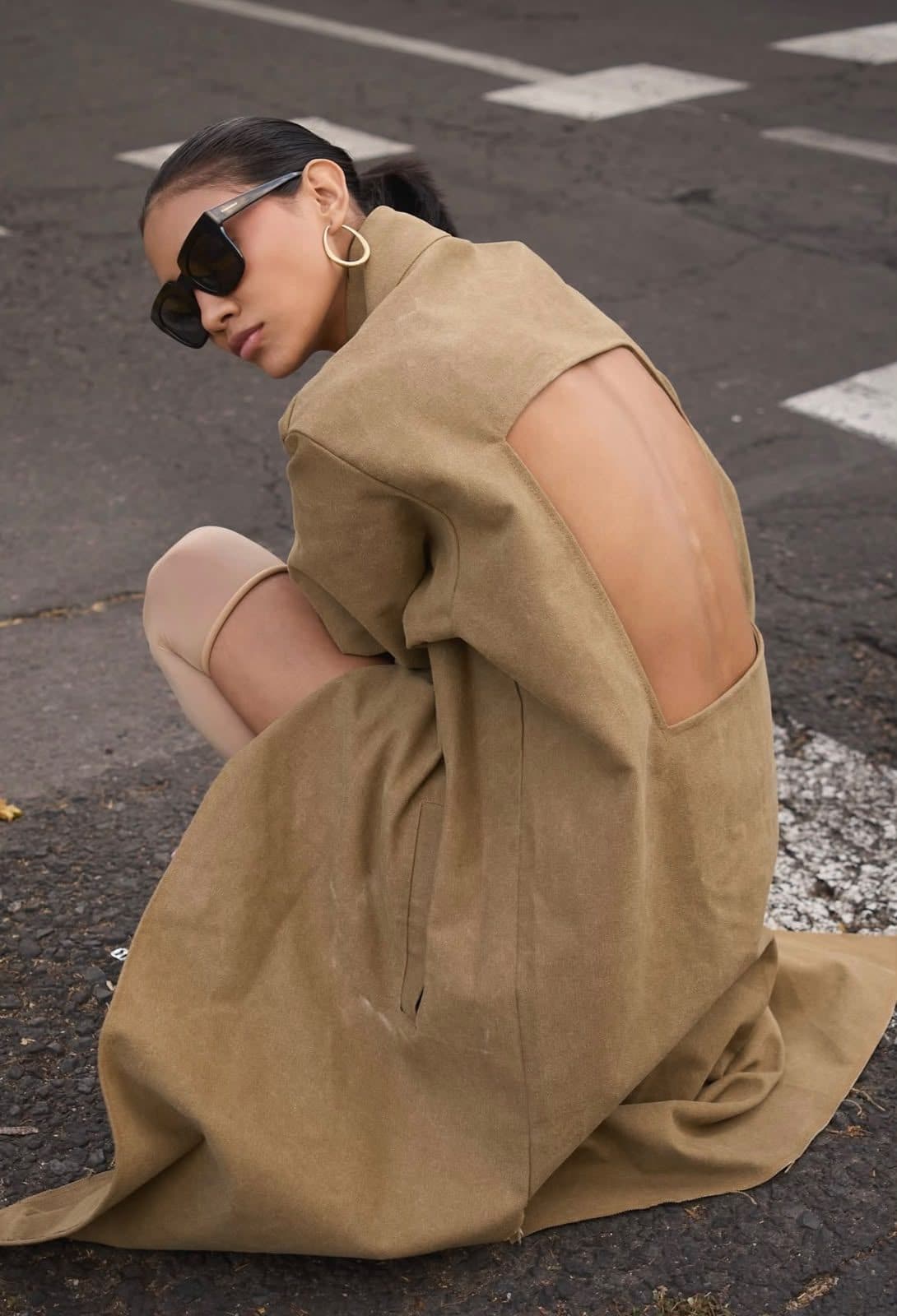 Model crouched on the street in the open-backed FRAME coat