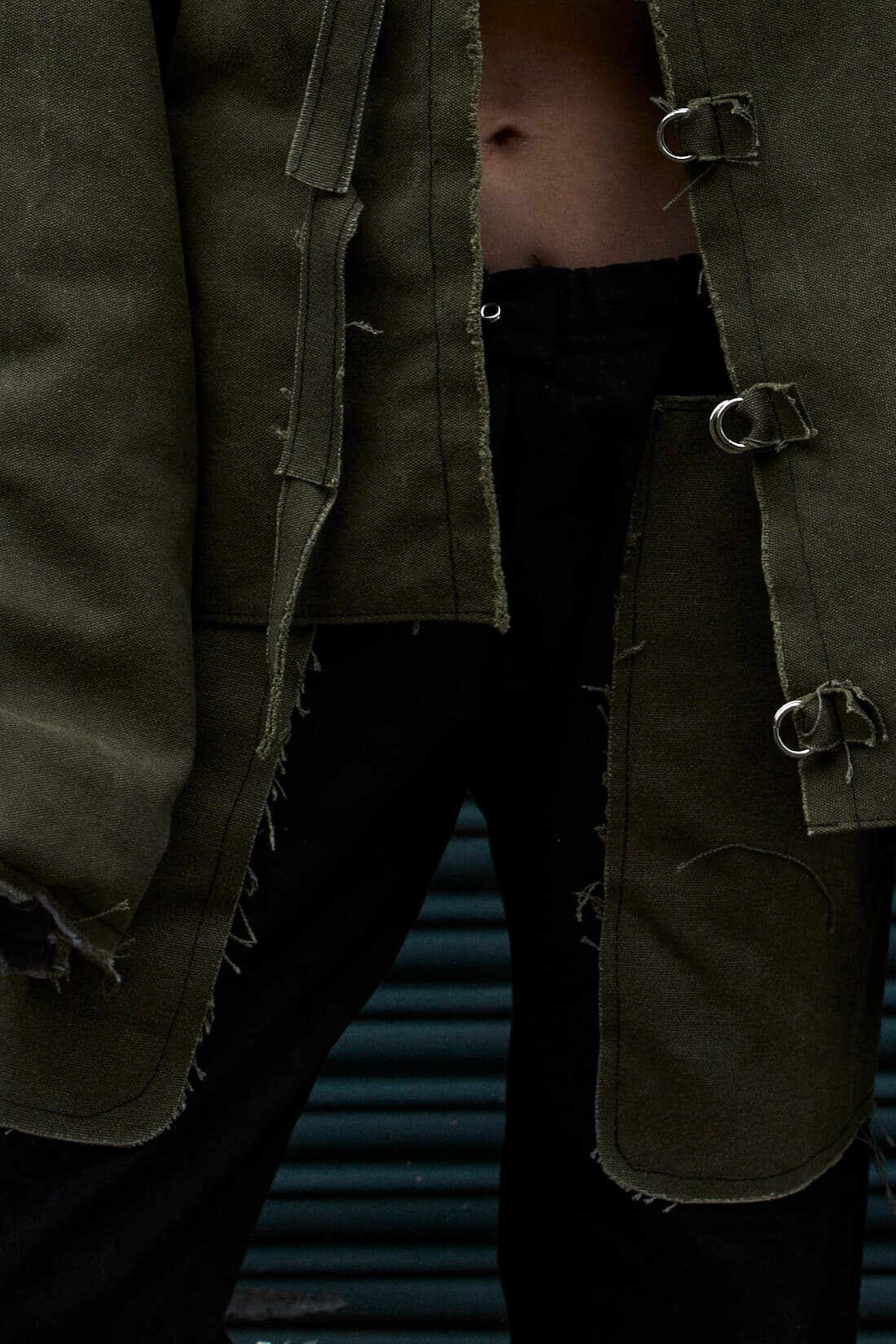 MOSS trousers: raw-edged green tapestry pocket on black denim, under the AKIN jacket